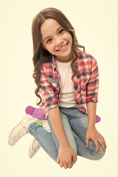 ハッピーライド。子供の女の子幸せなペニーボードに座っている。もともと女の子スケートボードとして設計された。現代の十代の趣味。女の子幸せな顔ペニーボードの白い背景に座っている。ペニーボードに乗る方法を学ぶ — ストック写真
