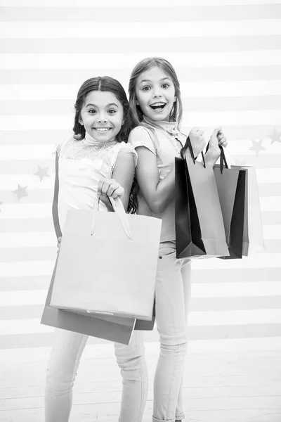 A las chicas les gusta comprar. Niños felices niñas pequeñas sostienen bolsas de compras. Disfruta de ir de compras con tu mejor amiga o hermana. Felicidad femenina. Los niños felices llevan paquetes de racimo. Compras con concepto de mejor amigo — Foto de Stock