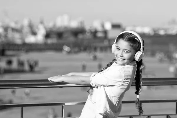 Не зупиняй музику. Щаслива дівчина носить навушники. Маленький фанат музики. Маленька дитина слухає музику на відкритому повітрі. Щаслива дитина. Тому що вулиці співають — стокове фото