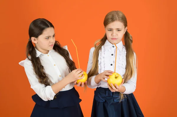 Повышение принятия студентами фруктов. Распространение бесплатных свежих фруктов в школе. Девочки школьная форма оранжевый фон. Школьницы едят яблоки. Школьный обед. Витаминное питание в школе — стоковое фото