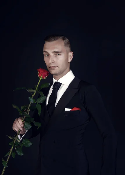 Mann mit roter Rose auf dunklem Hintergrund — Stockfoto