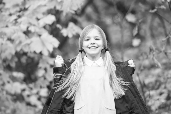 Kind blonde lange haren lopen in warme jas buiten. Meisje gelukkig in rode jas geniet van val park goed weer. Kind slijtage modieuze jas. Vallen van kleren en mode concept. Comfortabel en zorgeloos — Stockfoto