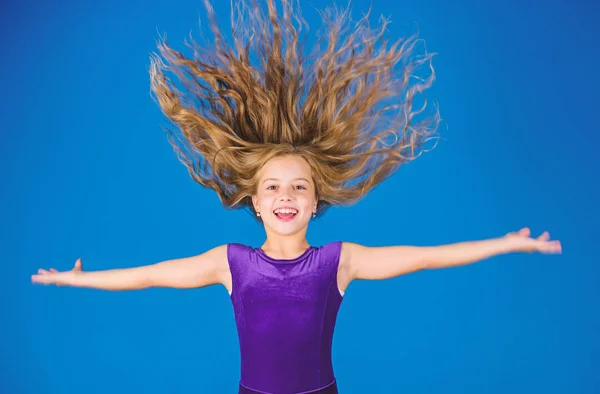 Ballroom latin dance hairstyles. Kid girl with long hair wear dress on blue background. Hairstyle for dancer. How to make tidy hairstyle for kid. Things you need know about ballroom dance hairstyle