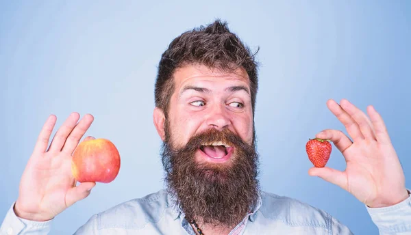 Βιταμίνη φρούτα διατροφή έννοια. Υγειονομική περίθαλψη δίαιτα βιταμίνη. Φρούτων και μούρων στα χέρια υγιή εναλλακτική λύση. Φρούτα ή μούρα άνθρωπος γένια χαμογελώντας κατέχει μήλο, φράουλα σε χέρια μπλε φόντο — Φωτογραφία Αρχείου