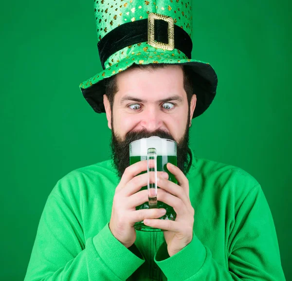 Una muerte rápida y fácil. Hipster en sombrero de duende sosteniendo taza de cerveza. Un hombre barbudo brindando por el día de San Patricio. Celebrando el día de San Patricio en el bar. Irlandés con barba bebiendo cerveza verde — Foto de Stock