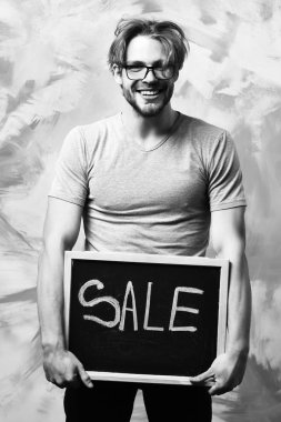 Beyaz sakallı seksi maço adam elinde satılık bir yazı tutuyor.