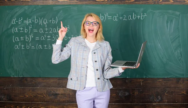 Online schooling concept. Woman wear eyeglasses holds laptop surfing internet. Educator smart clever lady with modern laptop searching information chalkboard background. Educational site for teachers — Stock Photo, Image