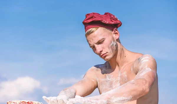 Chef en chapeau blanc sur le visage strict, ciel sur le fond. Homme avec le torse musculaire recouvert de farine semble attrayant. Homme avec l'aspect attrayant fonctionne comme boulanger, espace de copie. Concept de chef sexy — Photo