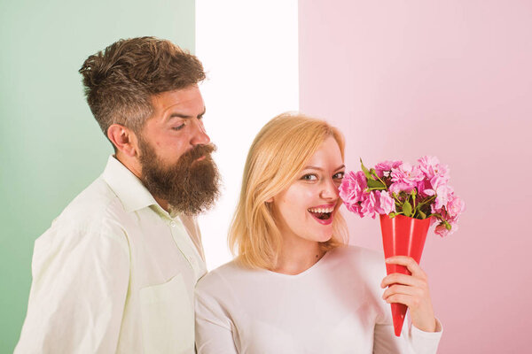 Woman enjoy fragrance bouquet flowers. Man with beard takes care about girlfriend happiness. Lady likes flower husband gifted her. Flowers delivery concept. Couple in love happy celebrate anniversary