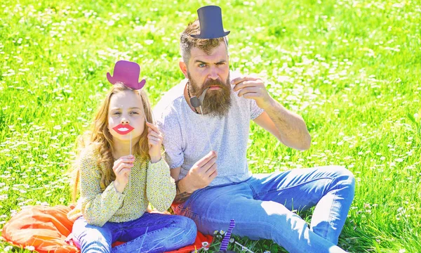 Aristocrates concept. Vader en dochter zit op gras op grassplot, groene achtergrond. Kind en vader poseren met hoge hoed, lippen en pijp foto stand kenmerken. Familie doorbrengen vrijetijdsbesteding buitenshuis — Stockfoto