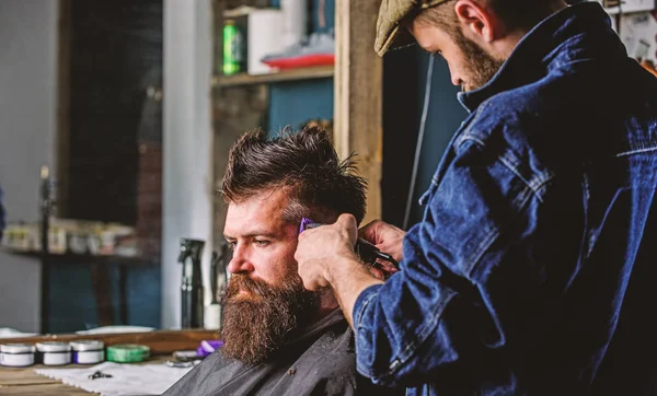 Peluquero con cortapelo recortando el pelo en el templo del cliente. Hipster cliente cortarse el pelo. Hipster concepto de estilo de vida. Peluquero con cortapelos trabaja en peinado para hombre barbudo barbería fondo — Foto de Stock