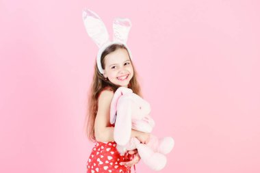 Tavşan kulaklar kafa bandı ile gülen çocuk. Paskalya ve bahar kutlama. Çocukluk, gençlik ve büyüme. Mutlu kız tutmak tavşan oyuncak pembe arka plan. Doğurganlık ve yeni hayat kavramı, kopyalama girintili
