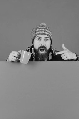 Sıcak şapkalı adam yeşil arka planda kahverengi bardak tutuyor.,