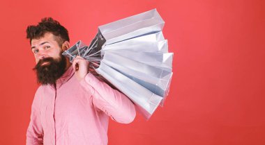 Hipster serin yüzündeki bağımlısı alışveriş veya Alışverişkoliğin. Satış sezon indirimlerle alışveriş adam. Alışveriş kavramı. Sakal ve bıyık taşır alışveriş torbaları omuz, kırmızı zemin üzerine olan adam