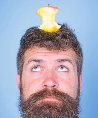 Adam yakışıklı hipster uzun sakal neredeyse kafasına elma güdük hedef olarak yem. Canlı hedef kavramı. Kilo kaybı gol. Hipster sürpriz yüz baş mavi arka plan üzerinde elma güdük hedefle yakın