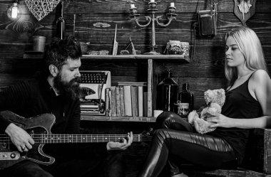 Romantik tarih kavramı. Adam oyun gitar Bayan ise oyuncak ayı elinde tutar. Çift Romantik akşam, ahşap iç arka plan geçirmek. Rahat yüzleri aşık çift romantik atmosferinin keyfini çıkarın.