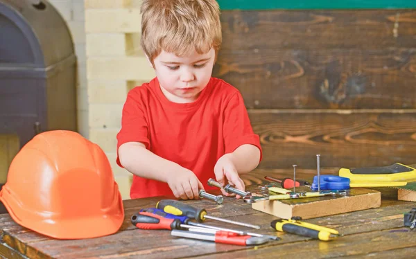 Boy holding two long metal bolts with screw nuts in his hands. Kid playing with tools. Educational game concept — Stock Photo, Image