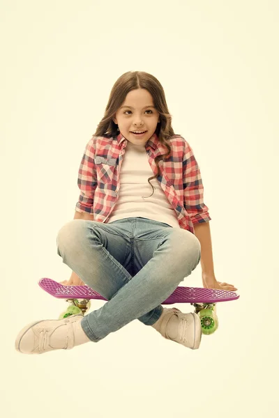 Duduk dan bersantai. Gadis kecil yang santai duduk di papan sen. Belajar bagaimana naik papan sen. Hobi remaja modern. Gadis wajah gembira duduk di penny board latar belakang putih. Awalnya dirancang sebagai skateboard gadis — Stok Foto
