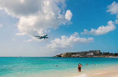 Philipsburg, Sint Maarten - 13 Şubat 2016: arazi maho sahil boyunca uçak. Jet Uçuş bulutlu gökyüzü düşük sinek. Mavi deniz uçakta. Caribbean Beach Tatil. Yolculuk tutkusu, seyahat ve gezi