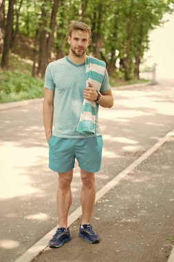 Adam atlet çalışan açık doğa arka plan sonra havlu ile. Atletik adam parkta eğitim. Atlet spor giysiler ve havlu eğitim. Runner iş günü güneşli bir gün. Spor ve egzersiz kavramı