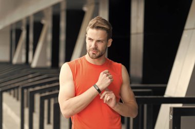 Devam edelim. Sporcu ile pedometre becerikli alet Stadyumu'nda eğitim. Spor araç konsepti. Adam atlet sıkı yüz Spor donatımı, kentsel arka plan ile. Atlet fitness izci veya adım sayar