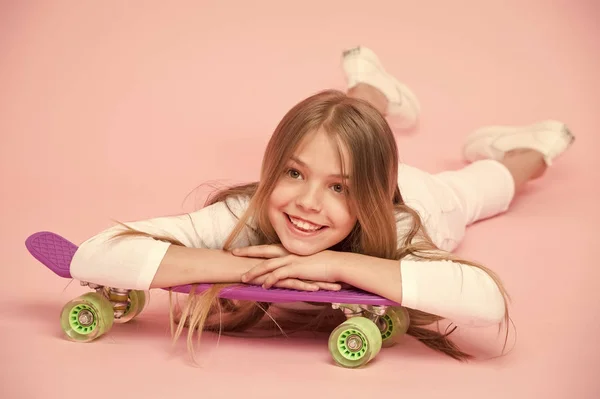十代の若者たちの趣味の概念。女の子は、スケート ボードやスポーティーなライフ スタイルに乗るが好きです。ペニー ボード、ピンクの背景とポーズ笑顔の女の子。子供のペニーのボードに乗る準備ができて長い髪の少女 — ストック写真