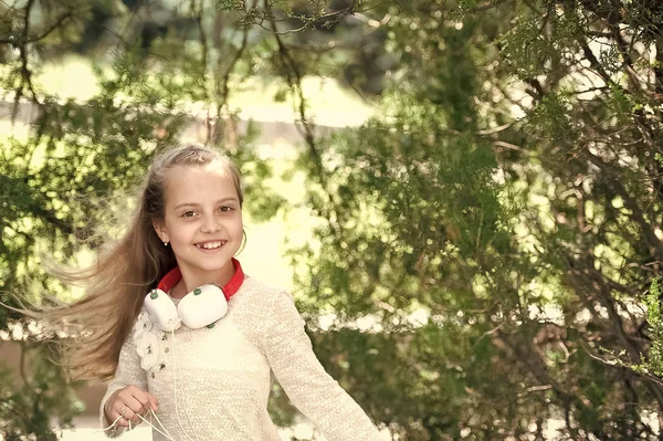 Criança gosta de música em fones de ouvido ao ar livre. Menina feliz dança à música no parque de verão. Kid dançarina sorrir com cabelos longos voando. Som melódico e mp3. Verão diversão e alegria — Fotografia de Stock