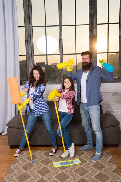 Familia mamá papá e hija con artículos de limpieza en la sala de estar. Nos encanta la limpieza y el orden. Limpiar juntos más fácil y más divertido. El cuidado familiar sobre la limpieza. Comienza a limpiar. Día de limpieza — Foto de Stock