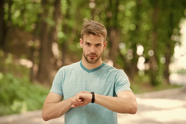 Atleta uomo sul viso rigoroso impostazione fitness tracker, sfondo della natura. Atleta con setola con fitness tracker o pedometro. Allenamento sportivo con gadget pedometro. Concetto gadget sportivo — Foto Stock