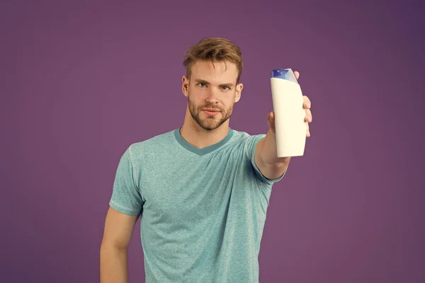 Hombre mantenga la botella de champú sobre fondo violeta. Hombre barbudo con tubo de gel sobre fondo morado. Cuidado de la piel y el cabello. Salud y salud. Cosmético para spa y bañera o ducha — Foto de Stock