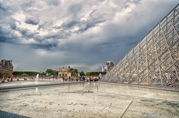 Paris, Fransa - 02 Haziran 2017: avlu bulutlu gökyüzü üzerinde cam piramit ve insanlar sıra ile Louvre Müzesi. Fransız başkentinin dönüm noktası. Tatil seyahat ve keşif kavramı — Stok fotoğraf