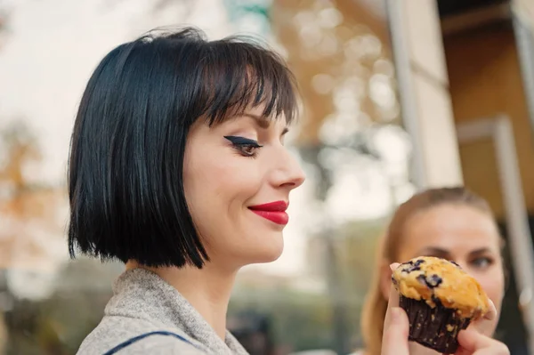 Glückliche Frauen betrachten Cupcake in Paris, Frankreich, Essen. Sinnliche Frau mit Muffin-Kuchen, Snack. Essen, Dessert, Snacks. Schönheit, Aussehen, Make-up. Hunger, Versuchung, Appetit — Stockfoto