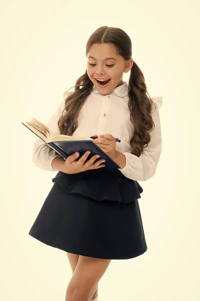 Niño pequeño con aspecto sorprendido aislado en blanco. Colegiala con pelo largo sostiene libro con pluma. Chica con uniforme escolar, de vuelta a la escuela. Un genio de la moda. Abre el libro a la vida —  Fotos de Stock