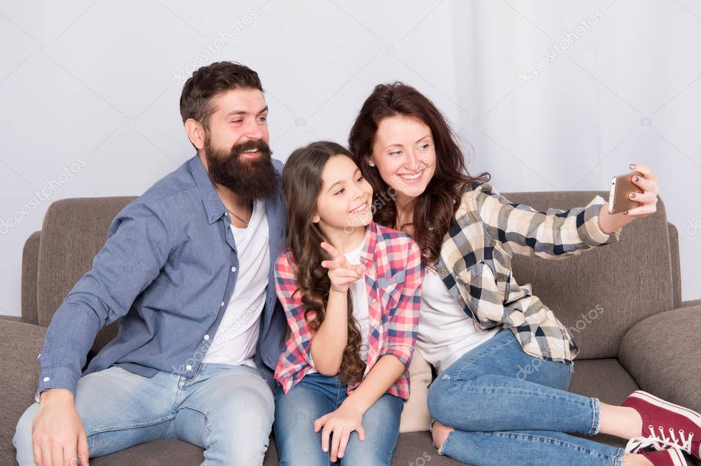 Capture happy moments. Family selfie. Family spend weekend together. Use smartphone for selfie. Friendly family having fun together. Mom dad and daughter relaxing on couch. Family posing for photo
