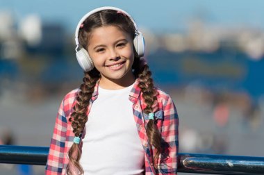 Çocuk açık havada müzik dinliyor modern kulaklıklar. Küçük kız şarkı kulaklığı dinliyor. Müzik hesabı çalma listesi. Müziğini özelleştir. Şehirli çocuk eğlencesi. Küçük çocuk dinleniyor. Gittiğin her yerde müzik