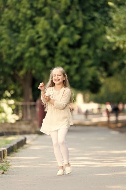 Çocuk mutlu ve neşeli parkta yürüyüş tadını çıkarın. Çocukluk kavramı. Kız mutlu güler yüz üzerinde yürür, Doğa arka plan üzerinde. Uluslararası Çocuk günü yürüyüşüne neşeli ifade ile çocuk kız