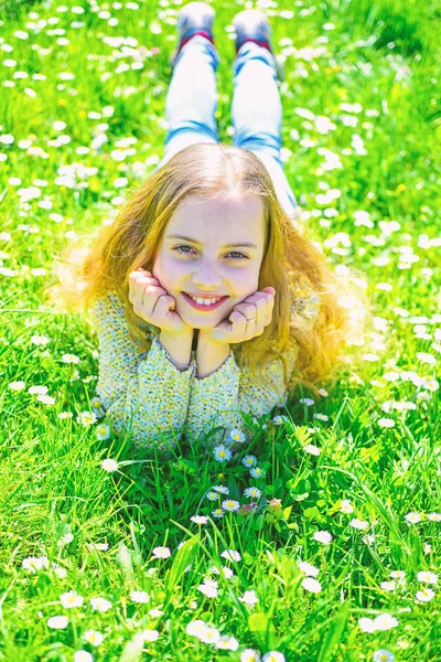 草地、緑色背景で草の上に横たわる少女。子は、草原に横たわっている間春の天候の良い日をお楽しみください。全盛期のコンセプトです。笑顔騎乗過ごすレジャー アウトドア — ストック写真