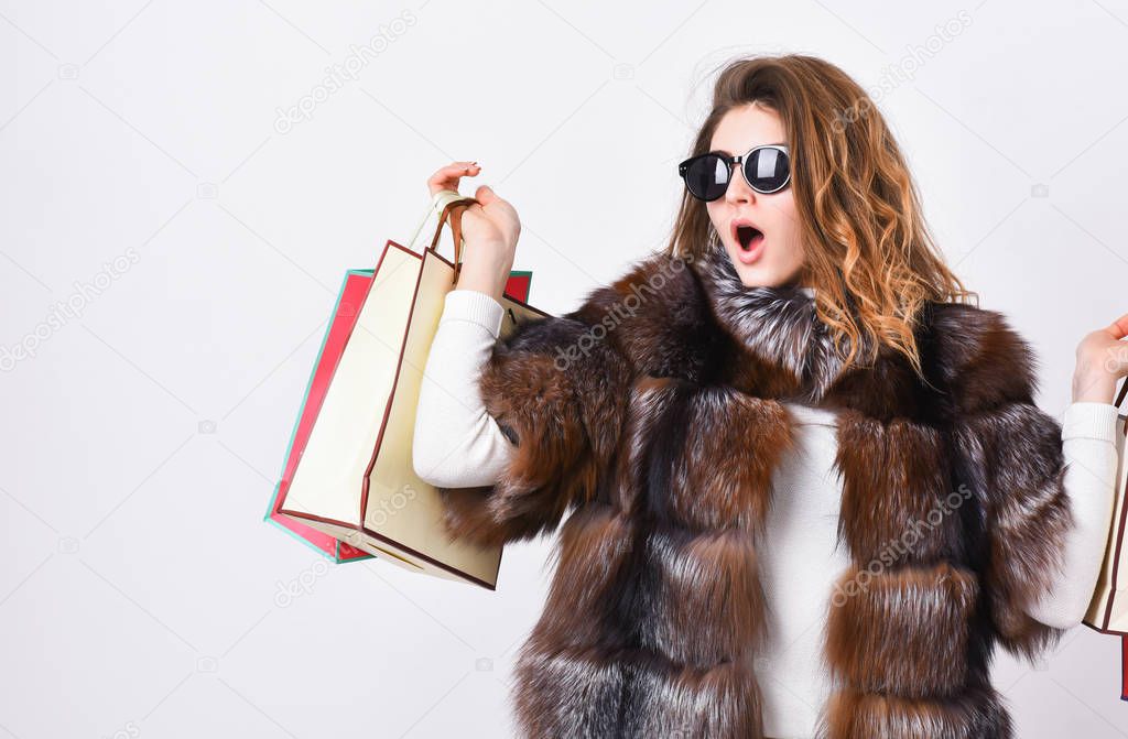 Girl wear sunglasses and fur coat shopping white background. Lady hold shopping bags. Discount and sale. Buy with discount on black friday. Shopping with promo code. Woman shopping luxury boutique