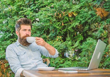 Hoş bir an. Hayattan zevk için zaman ayırın. Sakallı adam hipster yapmak kahve içmek için duraklatmak ve dizüstü bilgisayar ile oturup süre rahatla. Adam kahve rahatlatıcı Teras dalları arka plan içer. Aroma kapuçino