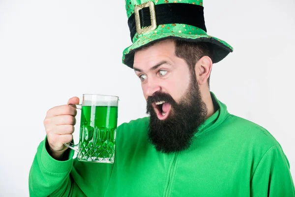 Celebrando el día de San Patricio en el bar. Un irlandés con barba bebiendo cerveza verde. Hipster en sombrero de duende sosteniendo taza de cerveza. Un hombre barbudo brindando por el día de San Patricio. Vamos a prepararnos para murmurar — Foto de Stock