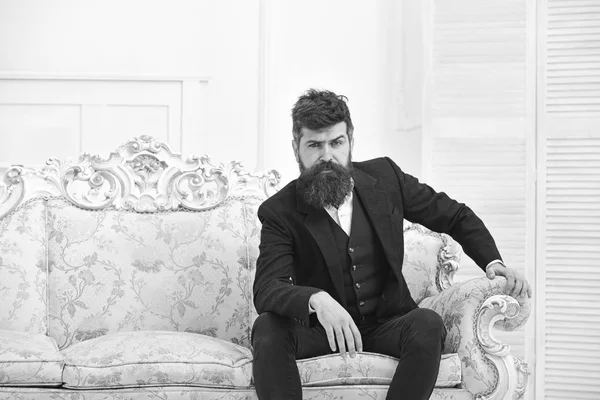 Мужчина с бородой и усами в классическом костюме, стильном модном наряде. Мачо привлекательный и элегантный на серьезном, законном лице, сидящий на старомодном роскошном диване. Концепция мужественности — стоковое фото