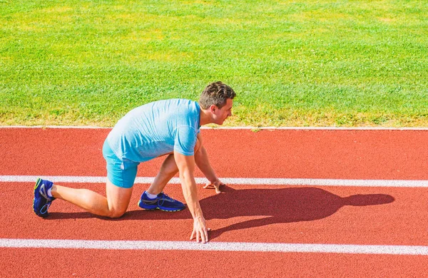 Corredor adulto preparar corrida no estádio. Como começar a correr. Conceito de motivação desportiva. Homem atleta corredor stand baixo início posição estádio caminho ensolarado dia. Corredor pronto para ir. Faça esforço para a vitória — Fotografia de Stock