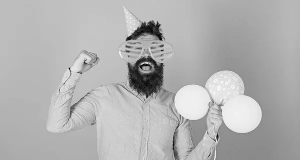 Hombre con barba espesa organizando actividades divertidas para niños. Hipster con mirada loca celebrando, concepto de felicidad. Hombre barbudo con gorra de cumpleaños, enormes gafas de lujo y camisa rosa sobre fondo azul —  Fotos de Stock