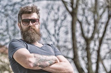 Sakal ve bıyık katı yüz, doğa arka plan, defocused olan adam. Sakallı adam modern güneş gözlüğü takıyor. Sakallı hippi güneşli günde şık ve kendinden emin görünüyor. Berber ve stil concep