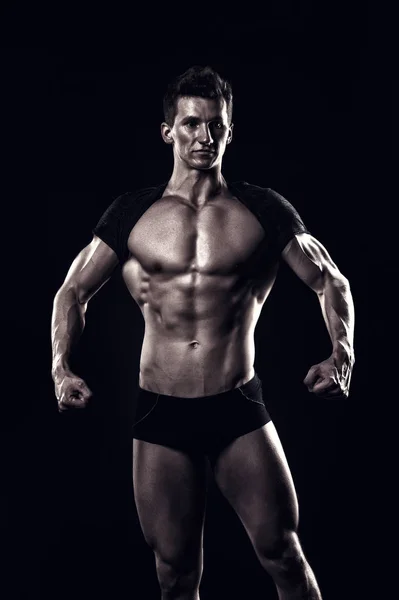 Bodybuilder montrer corps musculaire sur fond sombre — Photo