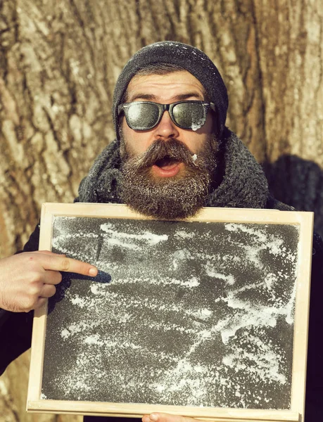 Upphetsad man, hipster, med skägg och mustasch i svarta solglasögon täckt med vit frost, med svarta tavlan vinterdag på naturlig bakgrund, kopiera spac — Stockfoto