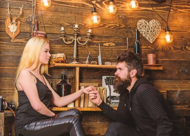 Çift gamekeepers evde, ahşap iç arka plan romantik akşamın. Kız ve erkek konsantre yüzleri sıcak atmosferinin keyfini çıkarın. Teklif kavramı. Aşık çift birlikte ellerini tutar