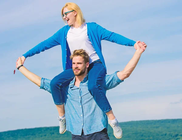 Soulmates enjoy freedom together. Couple happy date having fun together. Freedom concept. Man carries girlfriend on shoulders, sky background. Couple in love enjoy freedom outdoor sunny day