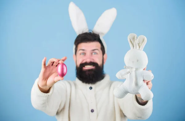 O grande festival da Primavera da Páscoa. Homem barbudo com brinquedo de coelho e ovo de Páscoa. Celebração da primavera. Hipster com longas orelhas de coelho segurando a lebre poedeira. Coelho da Páscoa entregando ovos coloridos — Fotografia de Stock