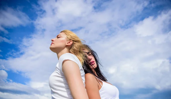 Freunde Mädchen, die auf dem Dach gegen den Himmel stehen. Designkonzept für Glück. zwei mädchen haben spaß huckepack auf outdoor. — Stockfoto